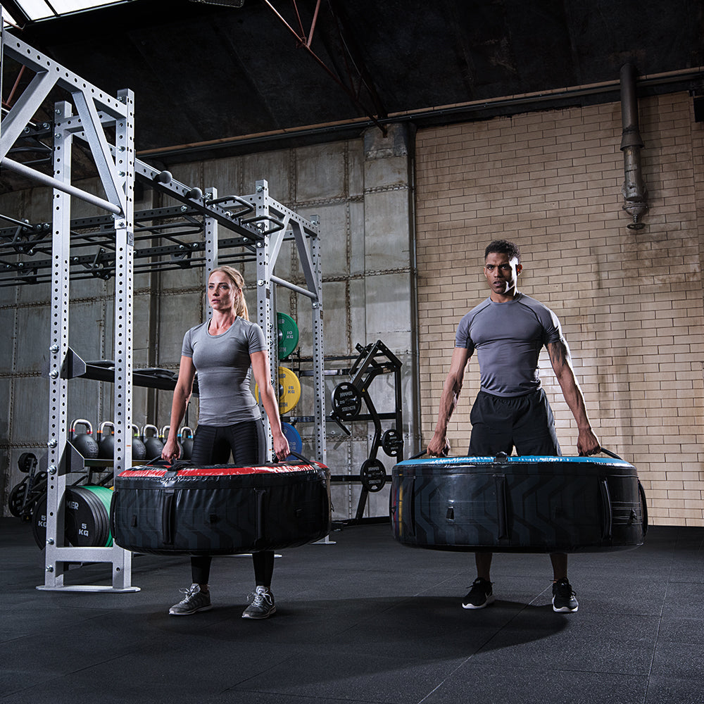 Exercisers farmer carrying flip tires during workout