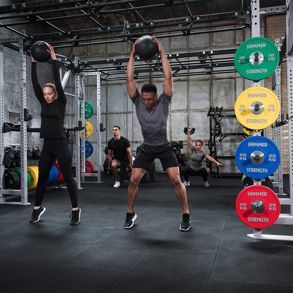 Man and woman using Hammer Strength Slam Balls in warehouse setting under a rack