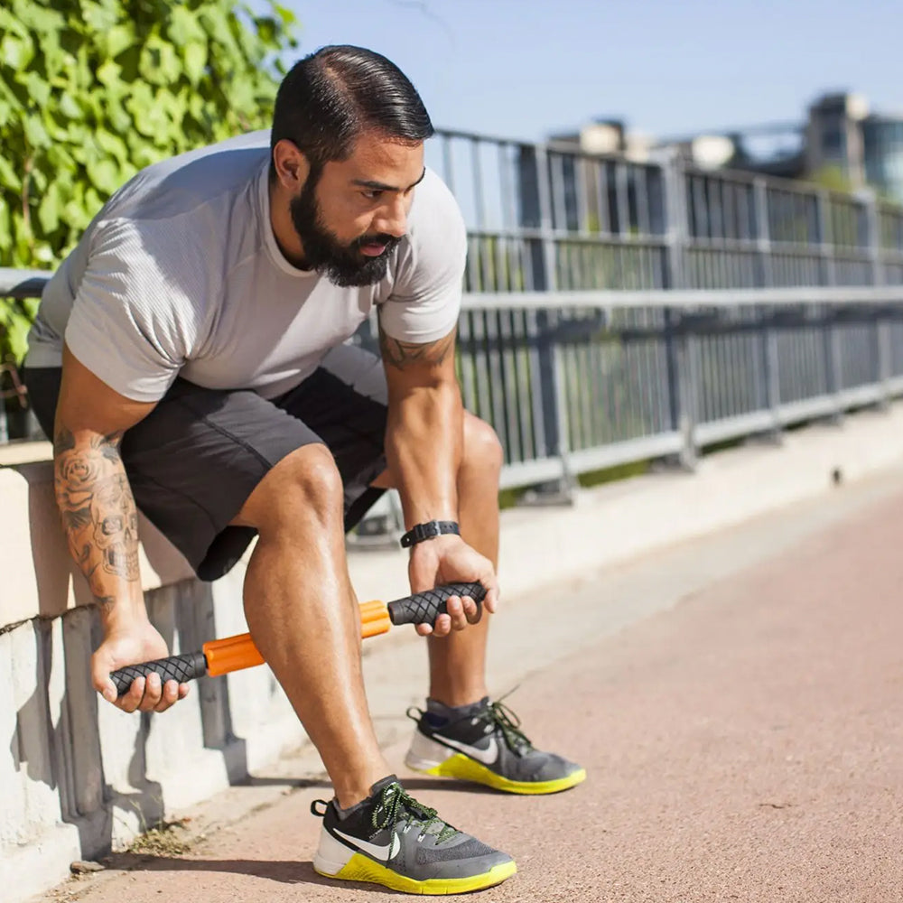 Exerciser massaging calves with Grid STK foam roller, outside