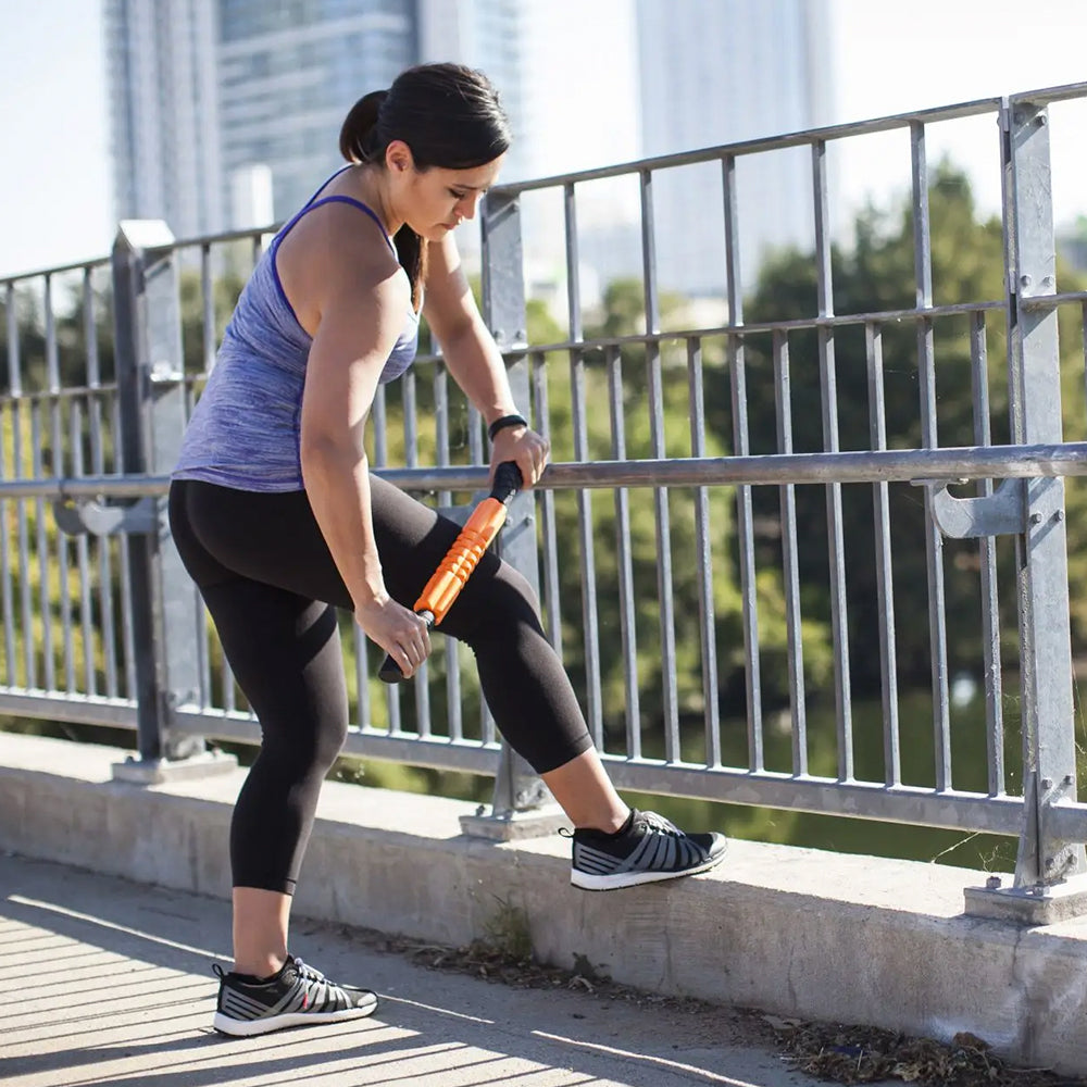 Exerciser massaging legs with Grid STK foam roller, outside